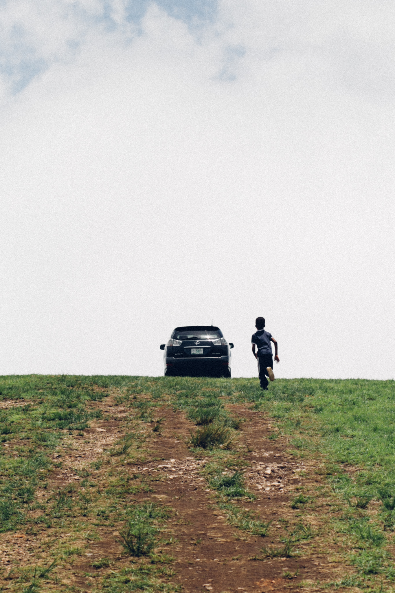 Boy chasing a car on a Hill top, Obudu